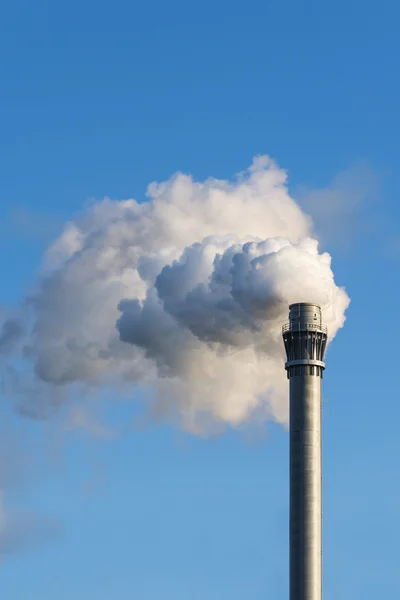 Industry chimney with clouds of smoke against the blue sky, copy space