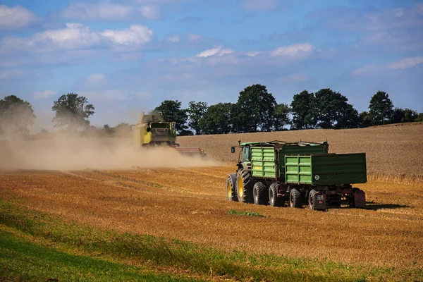 KALKHORST, GERMANY, AUGUST 16, 2016: John Deere tractor with two trailers follows the combine harvester
