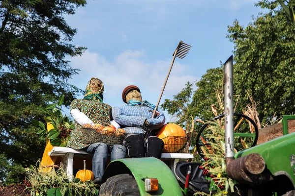 Scarecrow straw figures farmer and farmer\'s wife on an old tractor at the harvest festival thanksgiving