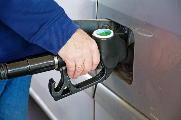 Male hand holding gasoline pump into the tank of a car