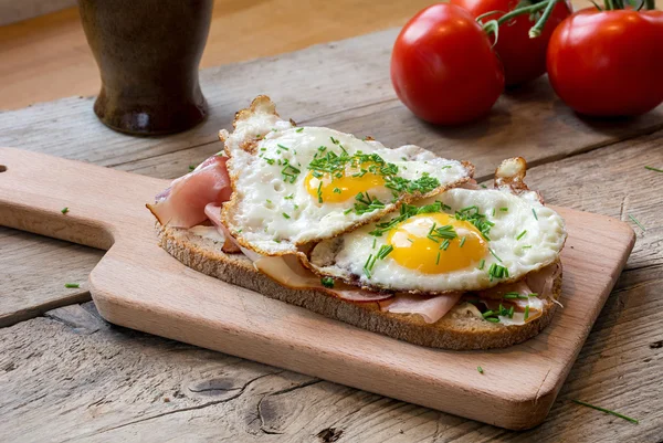 Country bread with ham and fried egg on a rustic table