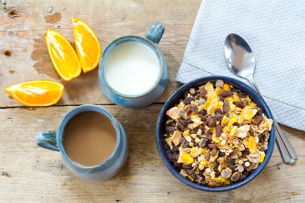 Breakfast granola with milk, coffee and sliced oranges on a wea