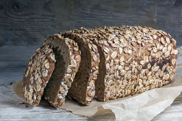 Dark bread loaf with whole grain and seeds on an old wooden boar