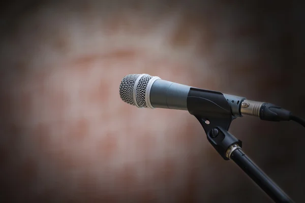 Microphone in front of an old blurred brick wall with a light sp