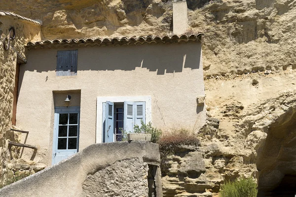 House facade in front of a cave in the mountain in the Provence,