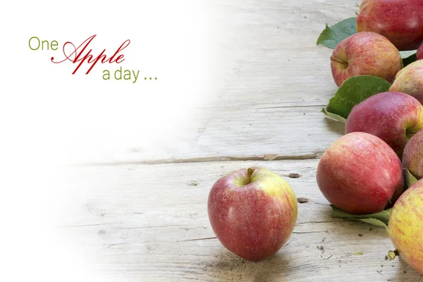 Red apples on rustic gray wood, background fade to white