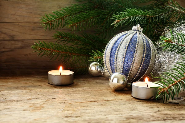 Silver and blue baubles, fir branches and candles as Christmas d