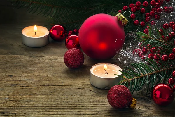 Red baubles, candles and fir branches as christmas decoration on