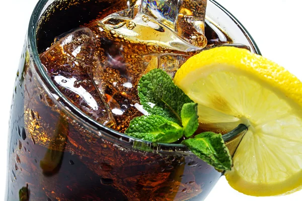 Top of a glass of cola or coke with ice cubes, lemon slice and peppermint garnish, closeup