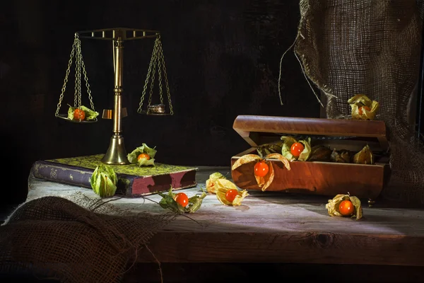 Physalis fruits escape from a jewelery box to a brass scale, still life metaphor