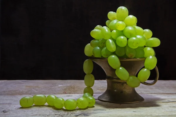 White grapes hanging like a necklace out of a brass bowl, vintag