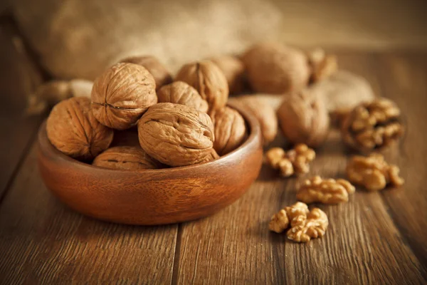 Walnut kernels and whole walnuts on rustic old wooden table