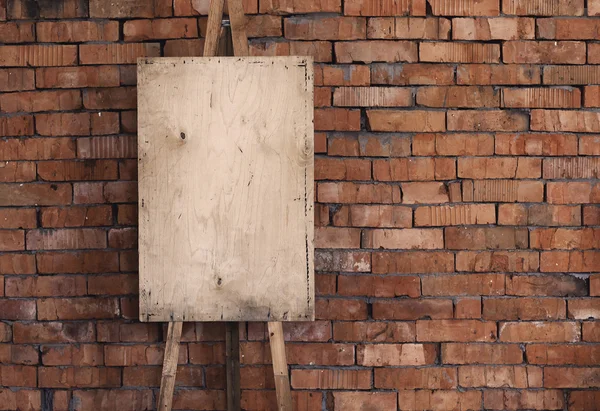 Blank grunge easel on a brick wall, art background