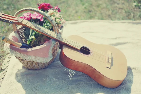 Guitar, basket with wine and bouquet of flowers. Vintage tender
