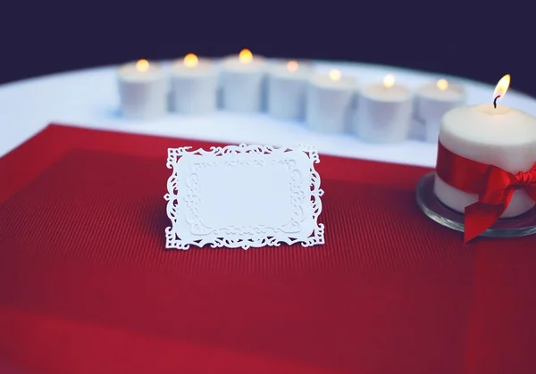 Paper card for a text on decorated table with burning candles. W
