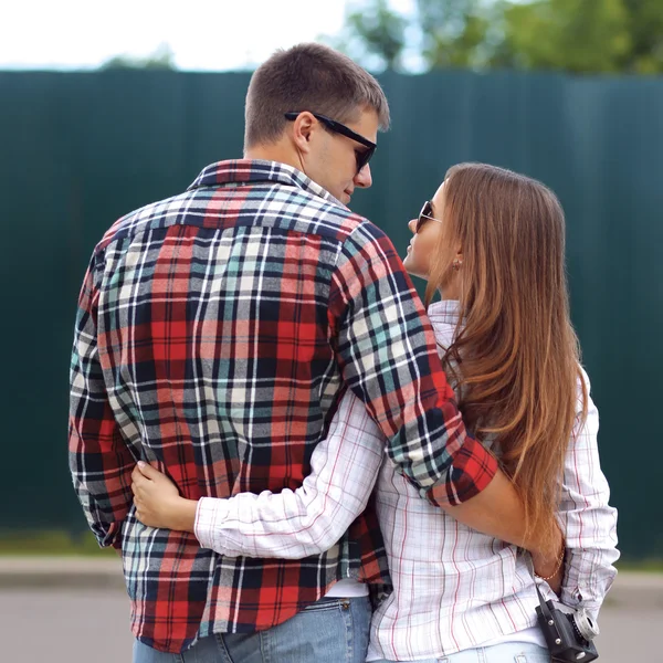 Young beautiful sweet couple hugging in the city, wearing checke