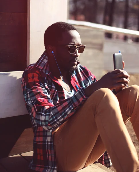 Lifestyle fashion portrait of stylish young african man listens
