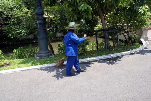 A street cleaner using a broom in a street in Bangkok, Thailand, Asia