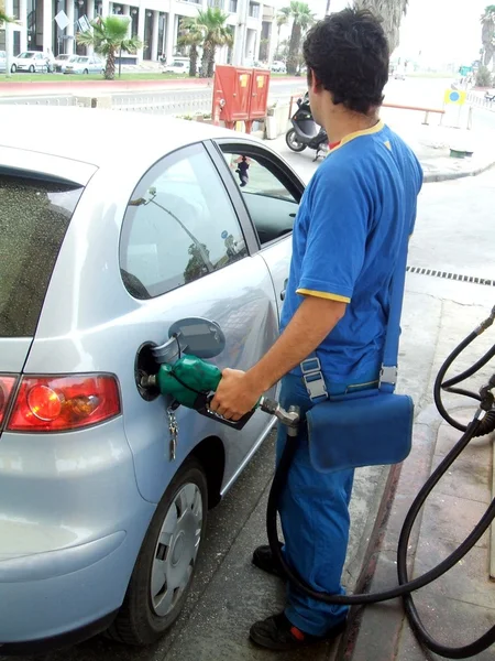 Petrol pump attendant refueling a car in a filling station