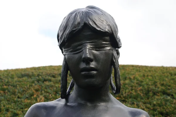 Blindfolded bronze woman statue at Chirk castle garden in Wrexham, Wales, England