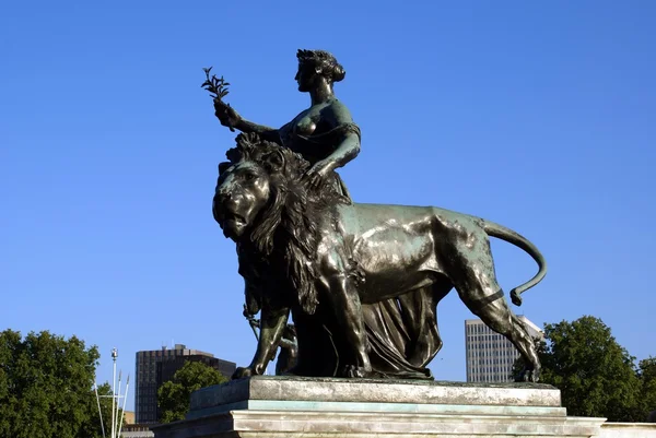 Statue of a woman and a lion in front of Buckingham Palace in London, England