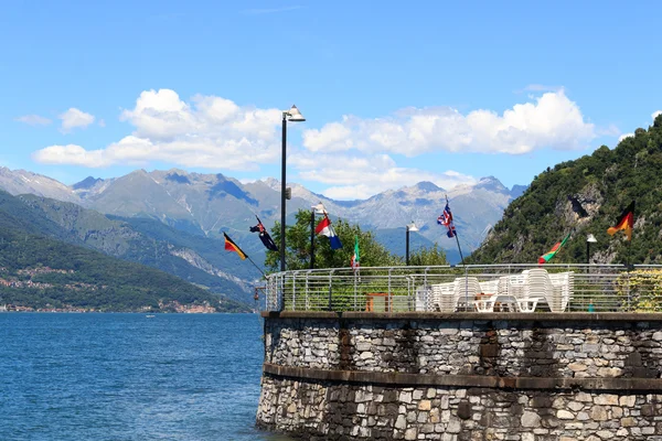 Different Flags at village Varenna at Lake Como with mountains in Lombardy, Italy