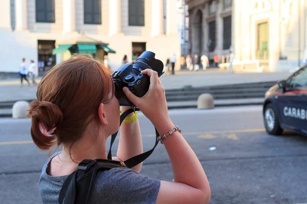 Tourist woman with camera taking picture of a tourist attraction in Genoa, Italy