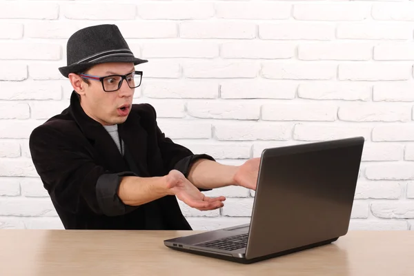 Shocked young business man using laptop looking at computer screen blown away in stupor sitting outside corporate office. Human face expression, emotion, feeling, perception, body language, reaction