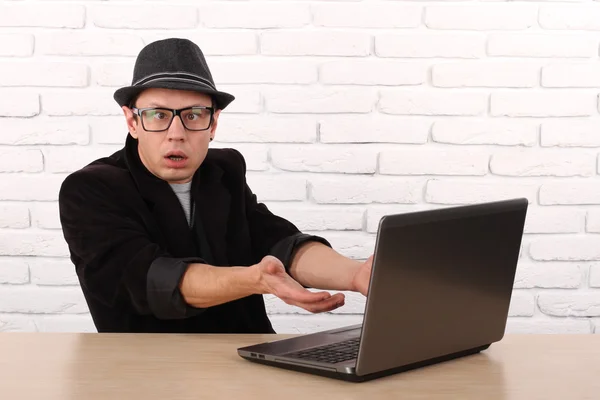 Shocked young business man using laptop looking at computer screen blown away in stupor sitting outside corporate office. Human face expression, emotion, feeling, perception, body language, reaction