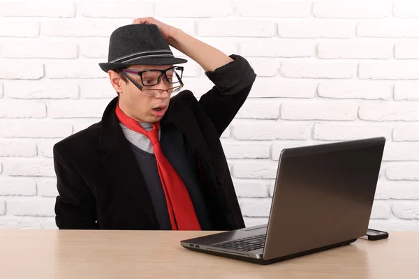 Shocked young business man using laptop looking at computer screen blown away in stupor sitting outside corporate office. Human face expression, emotion, feeling, perception, body language, reaction