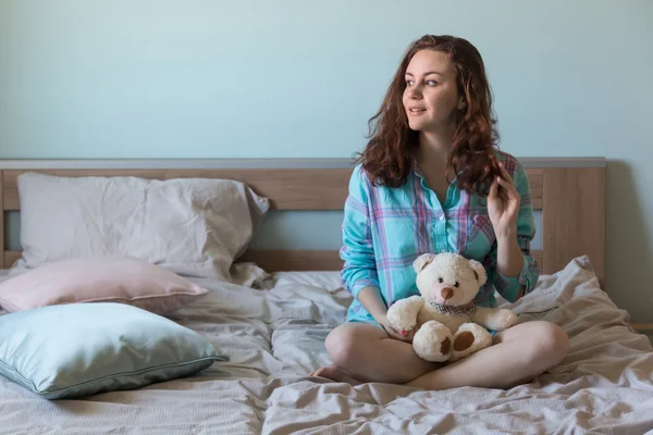Young beautiful woman with teddy bear in bed