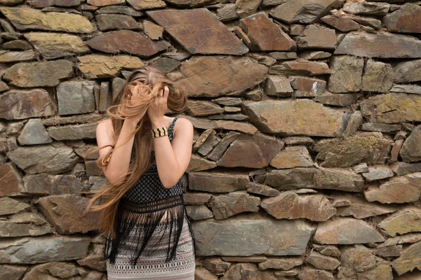 Young woman on the background of the old stone wall