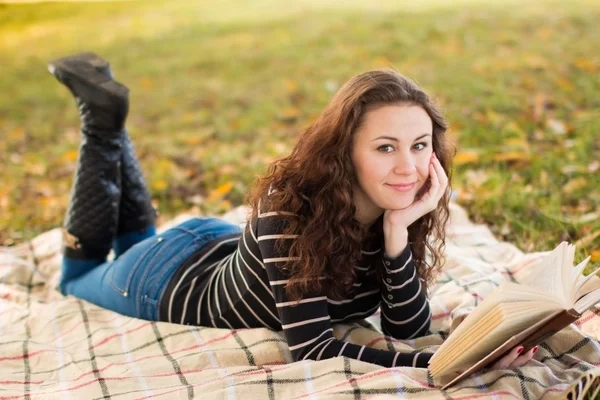 Young woman with book in the park in the autumn