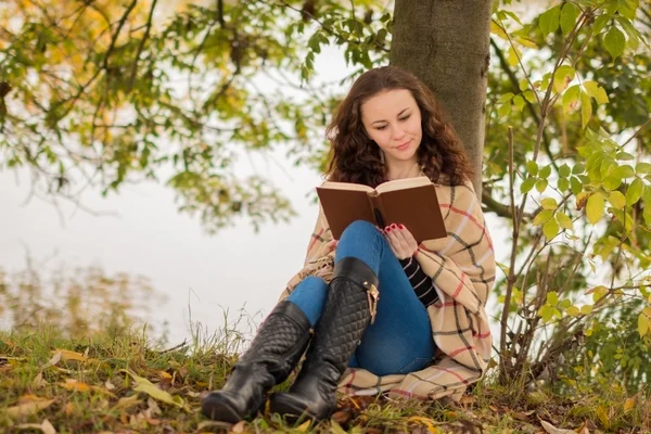 Young woman with book in the park in the autumn
