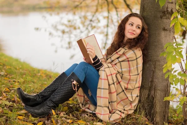 Young woman with book in the park in the autumn