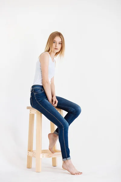 Young European woman posing in studio for test photo shoot showing different poses sitting on bar stool