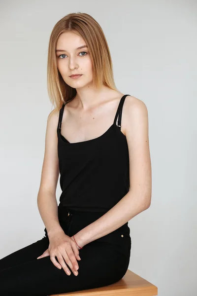 Young European woman posing in studio for test photo shoot showing different poses sitting on bar stool