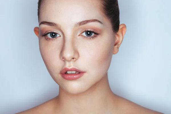 Glamour close up portrait of young beautiful woman model with trendy makeup. Fashion shiny highlighter on skin, sexy gloss lips make-up and dark eyebrows.