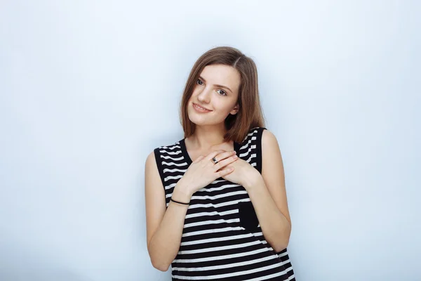 Portrait of happy young beautiful woman in striped shirt touching her neck posing for model tests against studio background