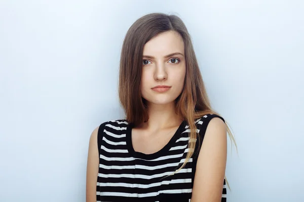 Portrait of happy young beautiful woman in striped shirt posing for model tests against studio background