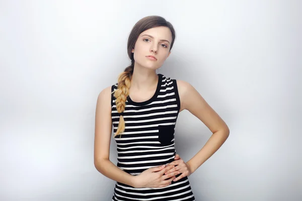 Portrait of naughty young beautiful woman in striped shirt contemptuous looking into camera posing for model tests against studio background