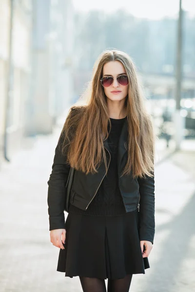 City portrait of young beautiful fashionable woman in sunglasses posibg outdoors at noon sun