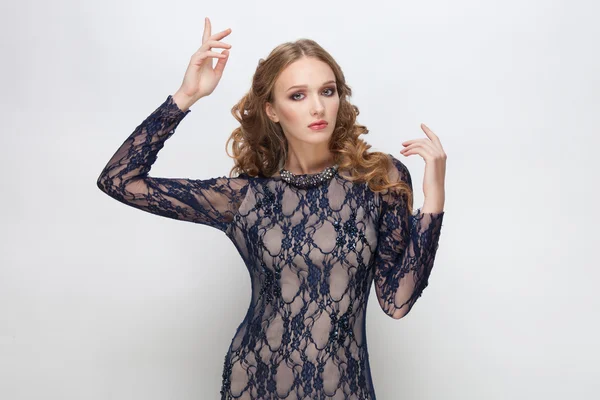 Young adorable blonde teen model in blue dress curly hairstyle doing an idea gesture posing on white studio background