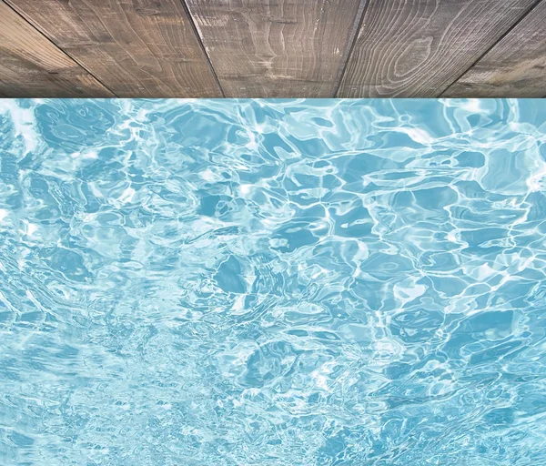 Blue swimming pool rippled water detail with wooden floor