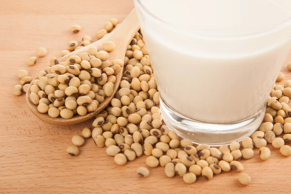 Soy milk in glass with soybeans and wooden spoon