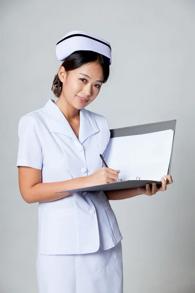 Young Asian nurse smile working on a report