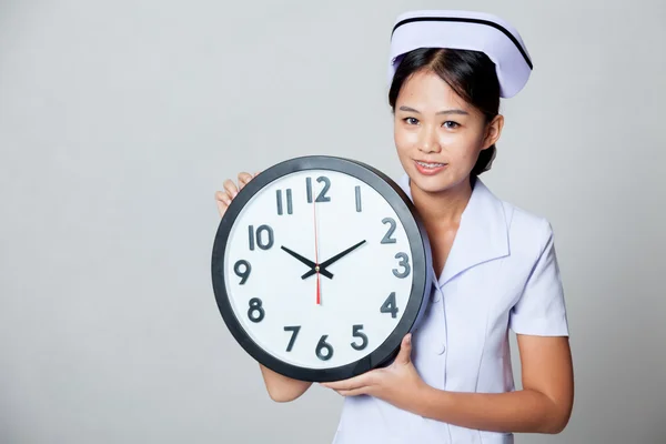 Young Asian nurse with a clock