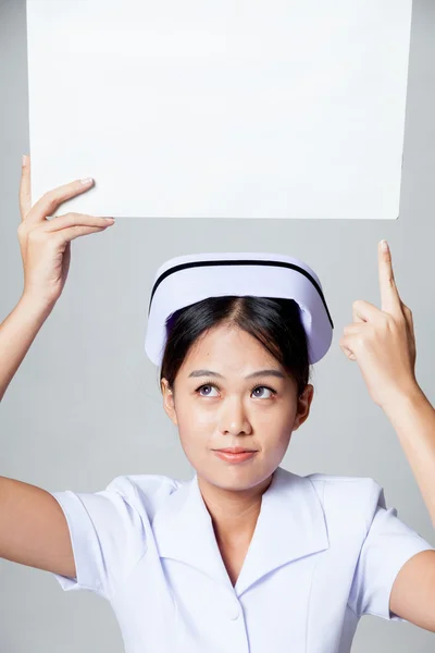 Young Asian nurse point to blank sign over her head