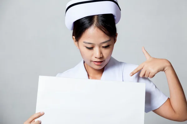 Young Asian nurse point down to blank sign