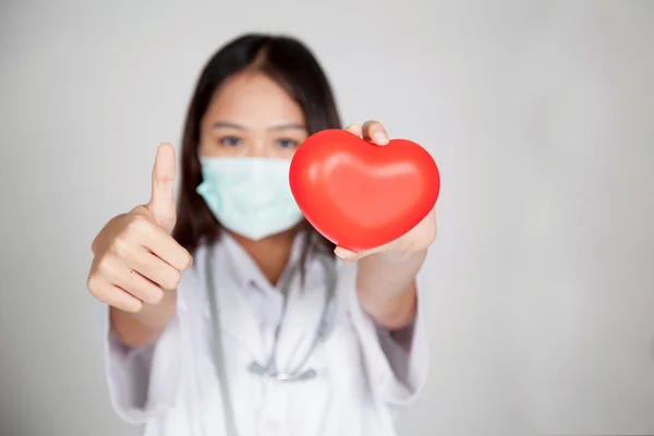 Young Asian female doctor thumbs up with red heart